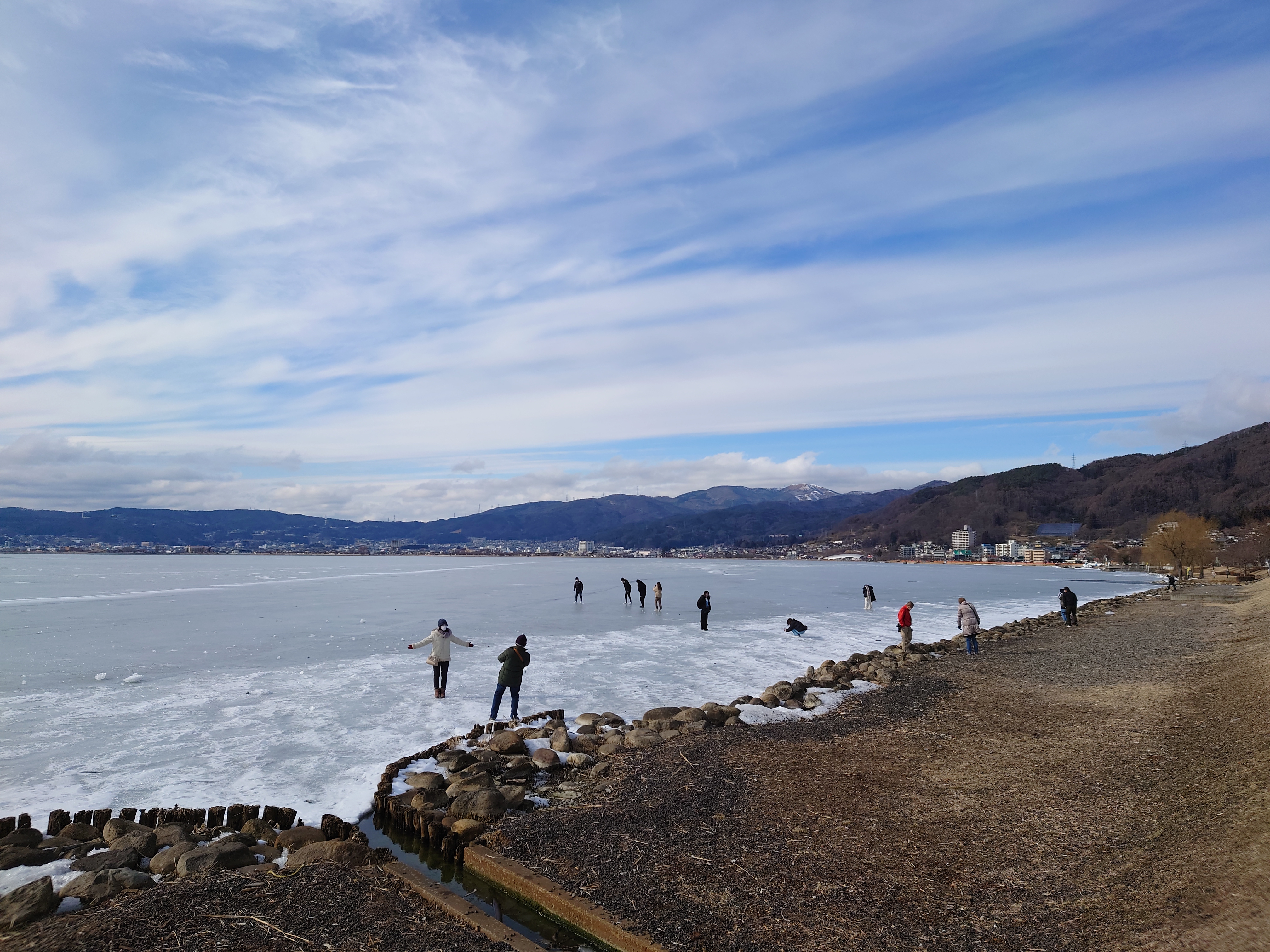 諏訪湖の岸辺近くに立つ人たち
