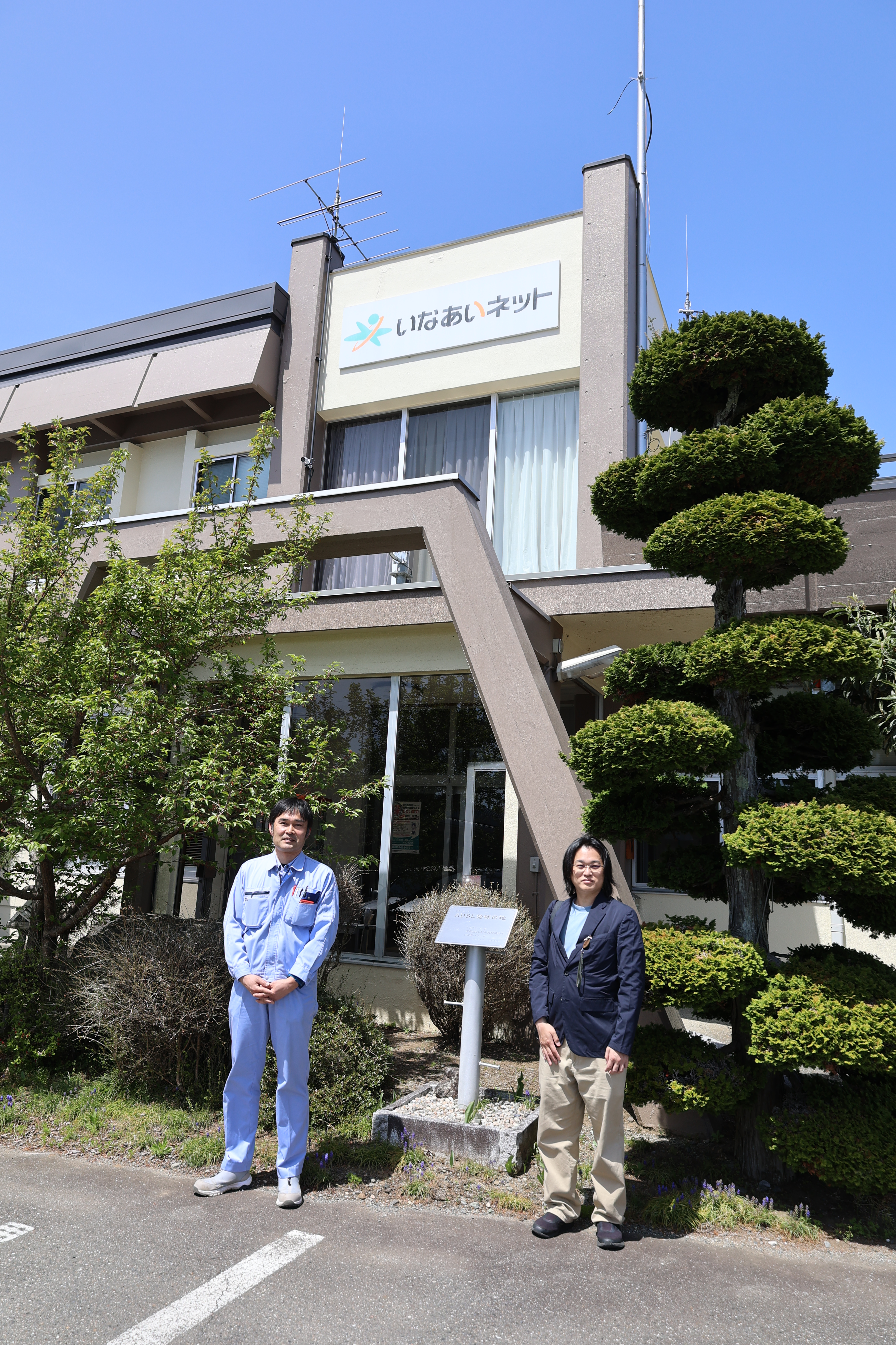 ADSL発祥の地の看板の前で、菊田さんと記念撮影（縦アングル）