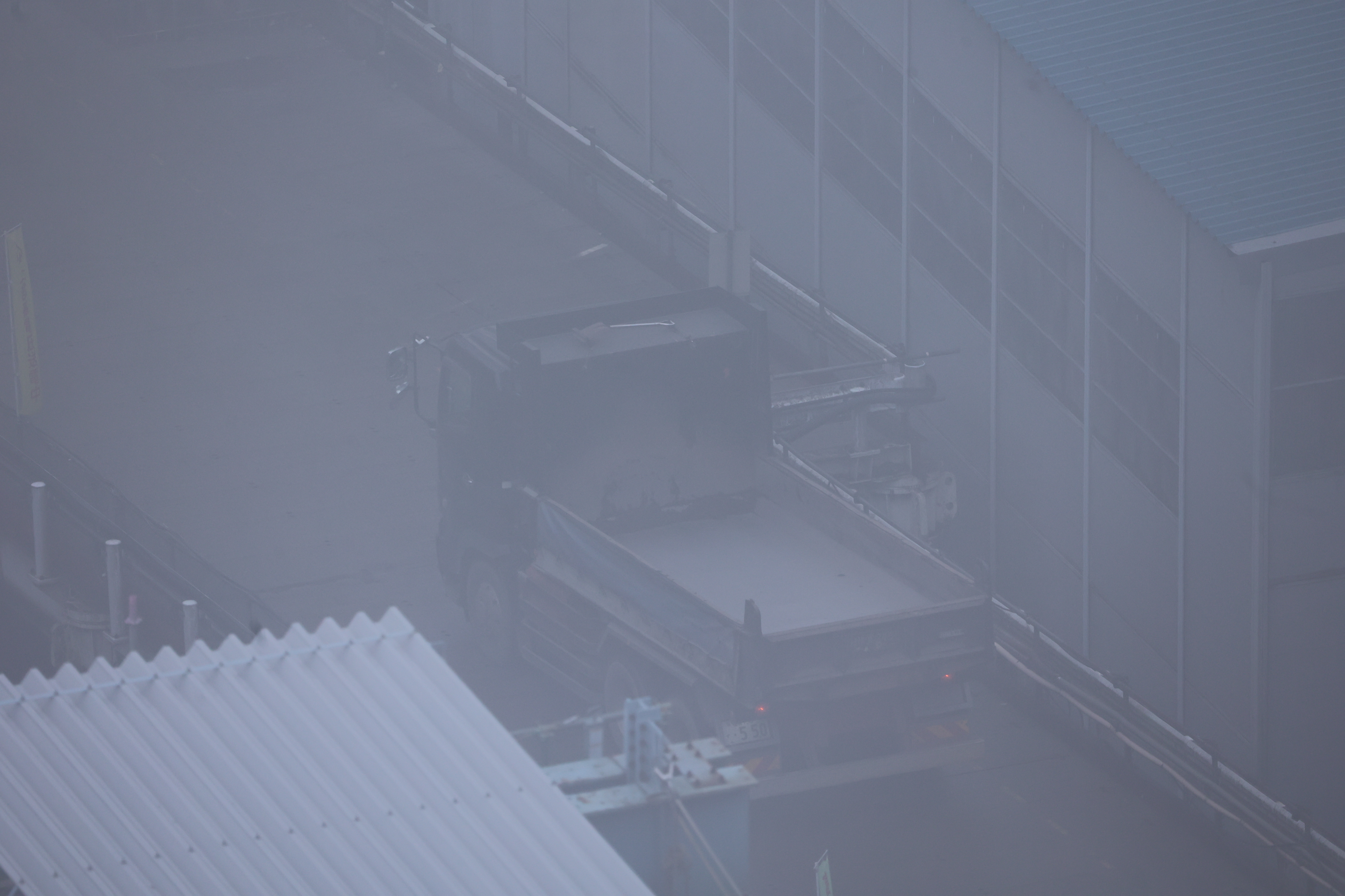 霧で良く見えない道を通過するダンプ