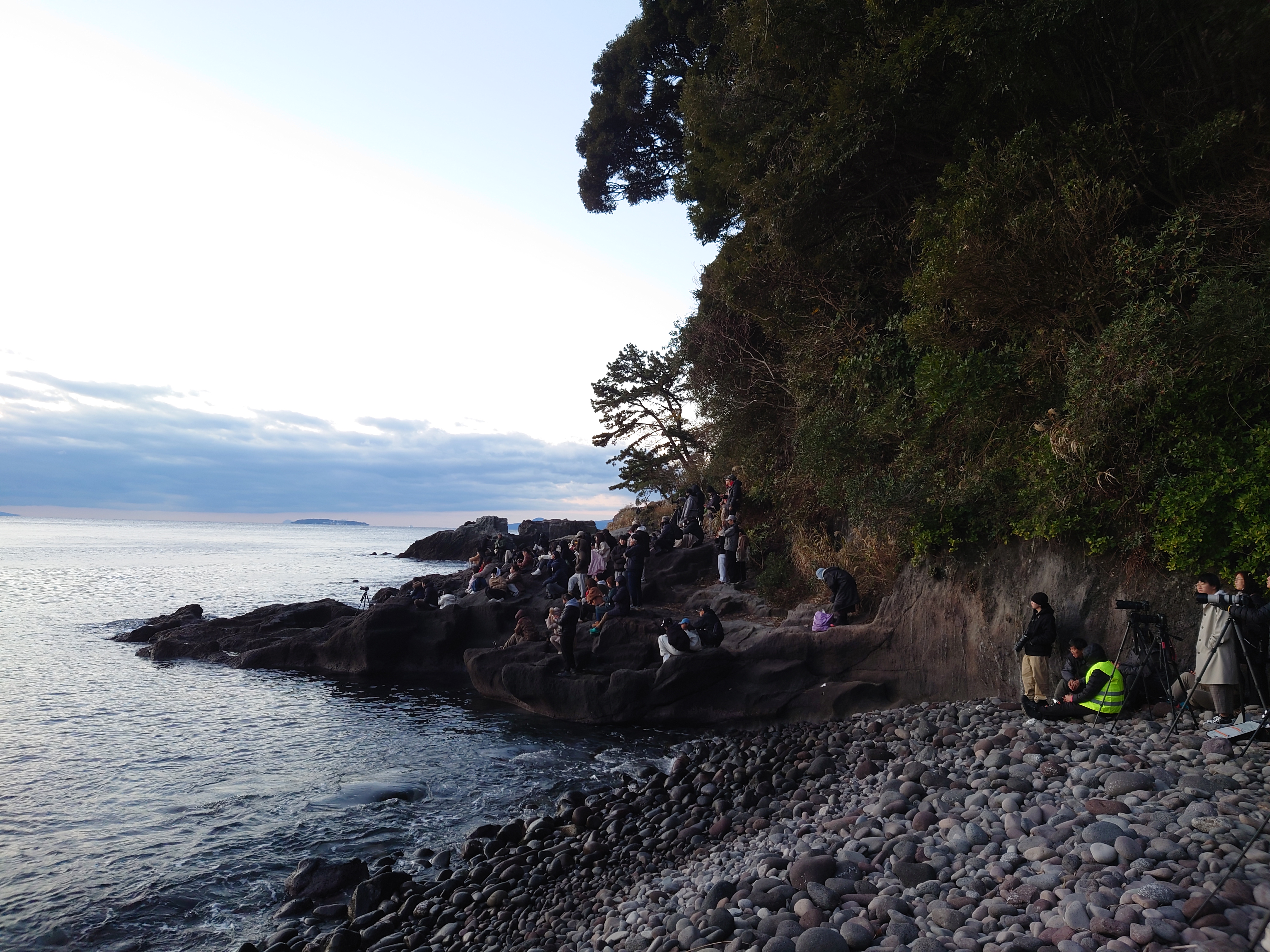 岩場で朝日を見る人たち