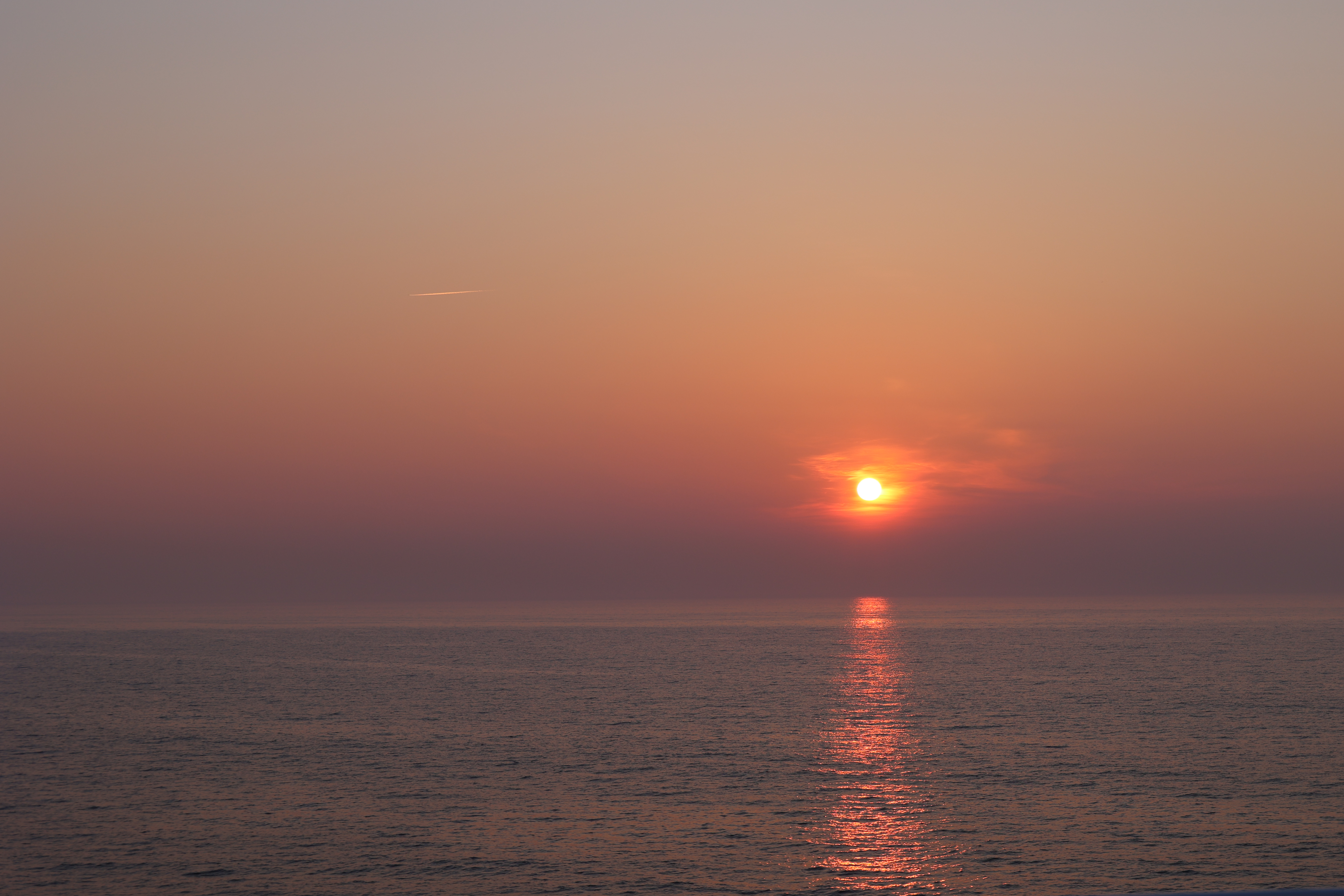 赤い太陽と飛行機雲（広角）